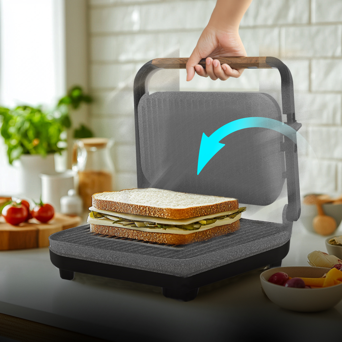 Una mano baja la tapa de una sandwichera gris con un sándwich dentro, sobre una encimera de cocina.