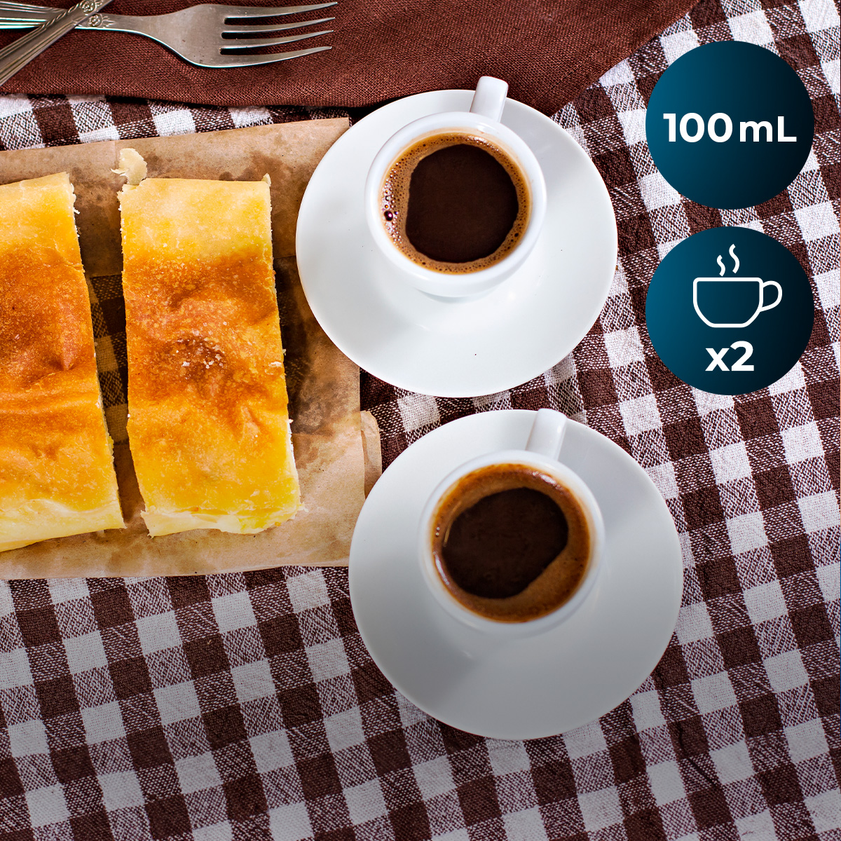 Due tazze di caffè e due fette di torta su una tovaglia a quadretti.