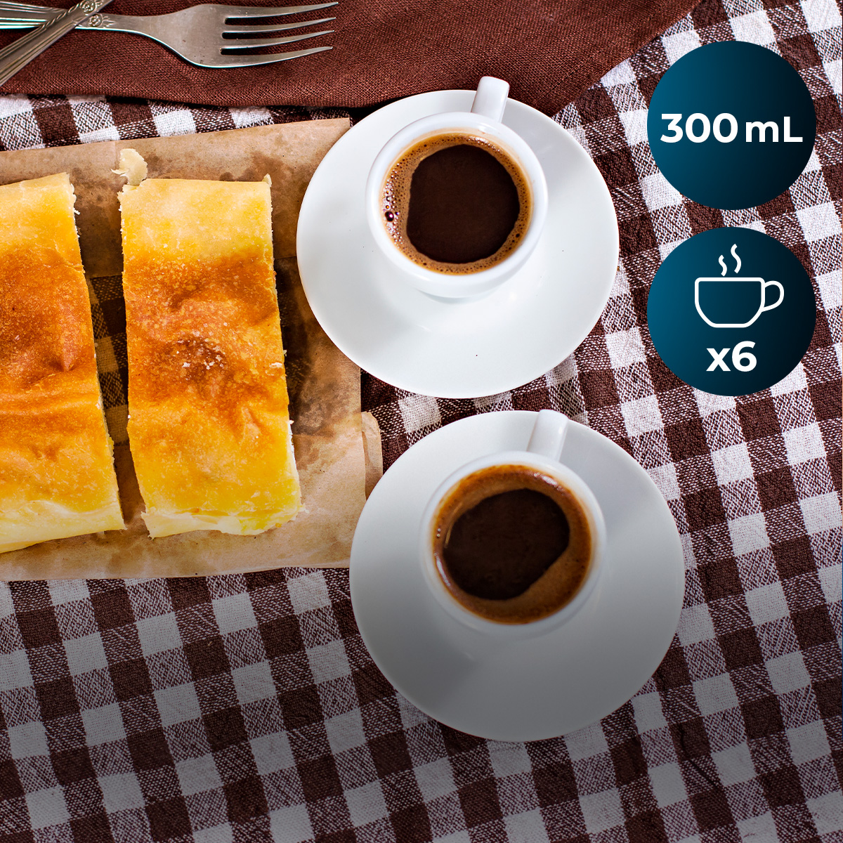 Due tazze di caffè e due fette di torta su una tovaglia a quadri.