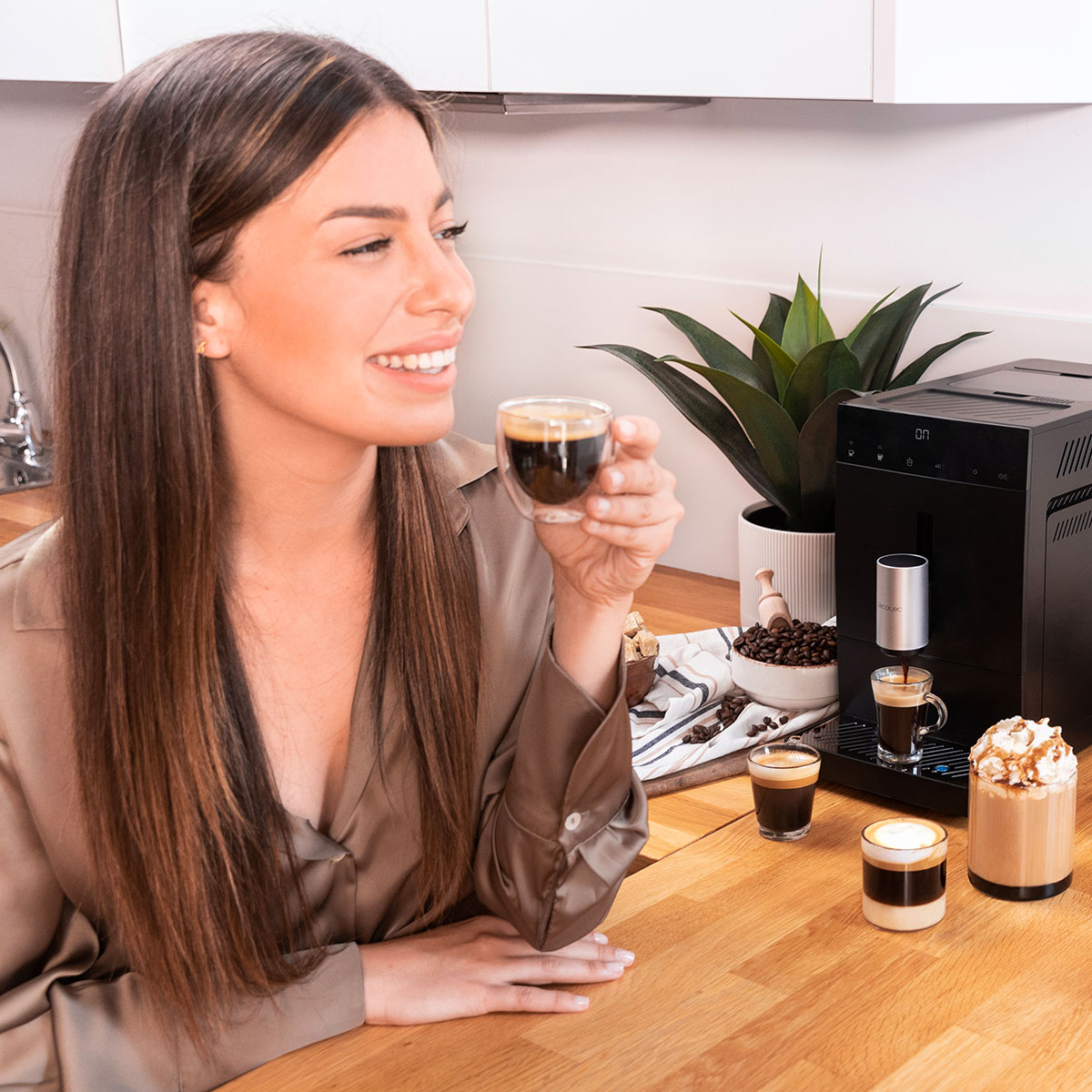 Una donna sorridente tiene una tazza di caffè accanto a una macchina per caffè espresso in cucina.