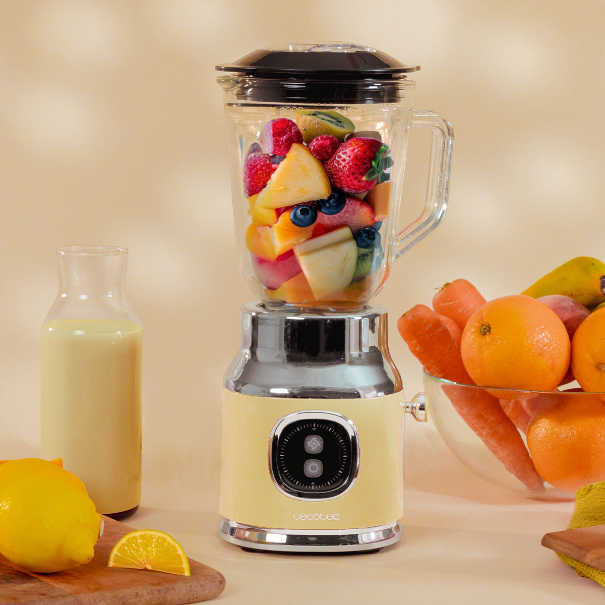 Ein gelber Standmixer mit frischen Früchten steht neben einer Flasche Saft und einer Schüssel Obst.