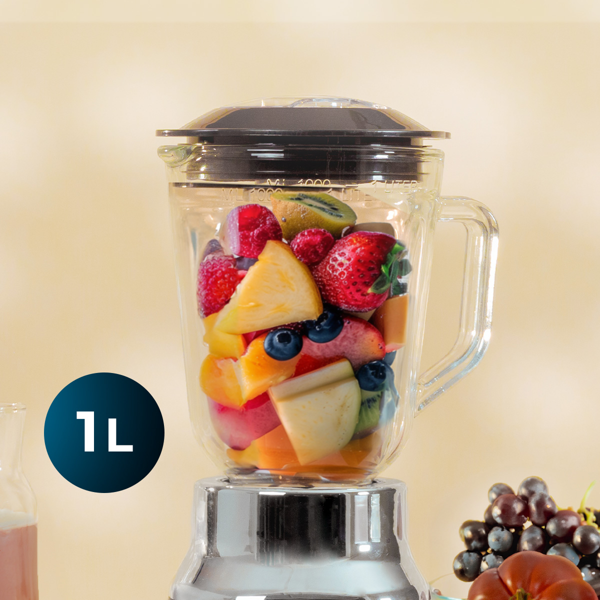 Un frullatore in vetro pieno di frutta fresca come fragole, ananas, kiwi e mirtilli su sfondo beige.