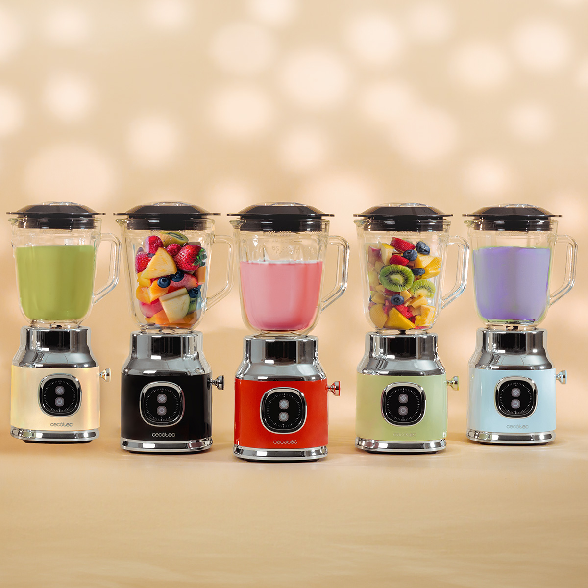 Cinque frullatori colorati con frullati e frutta fresca su una superficie beige.