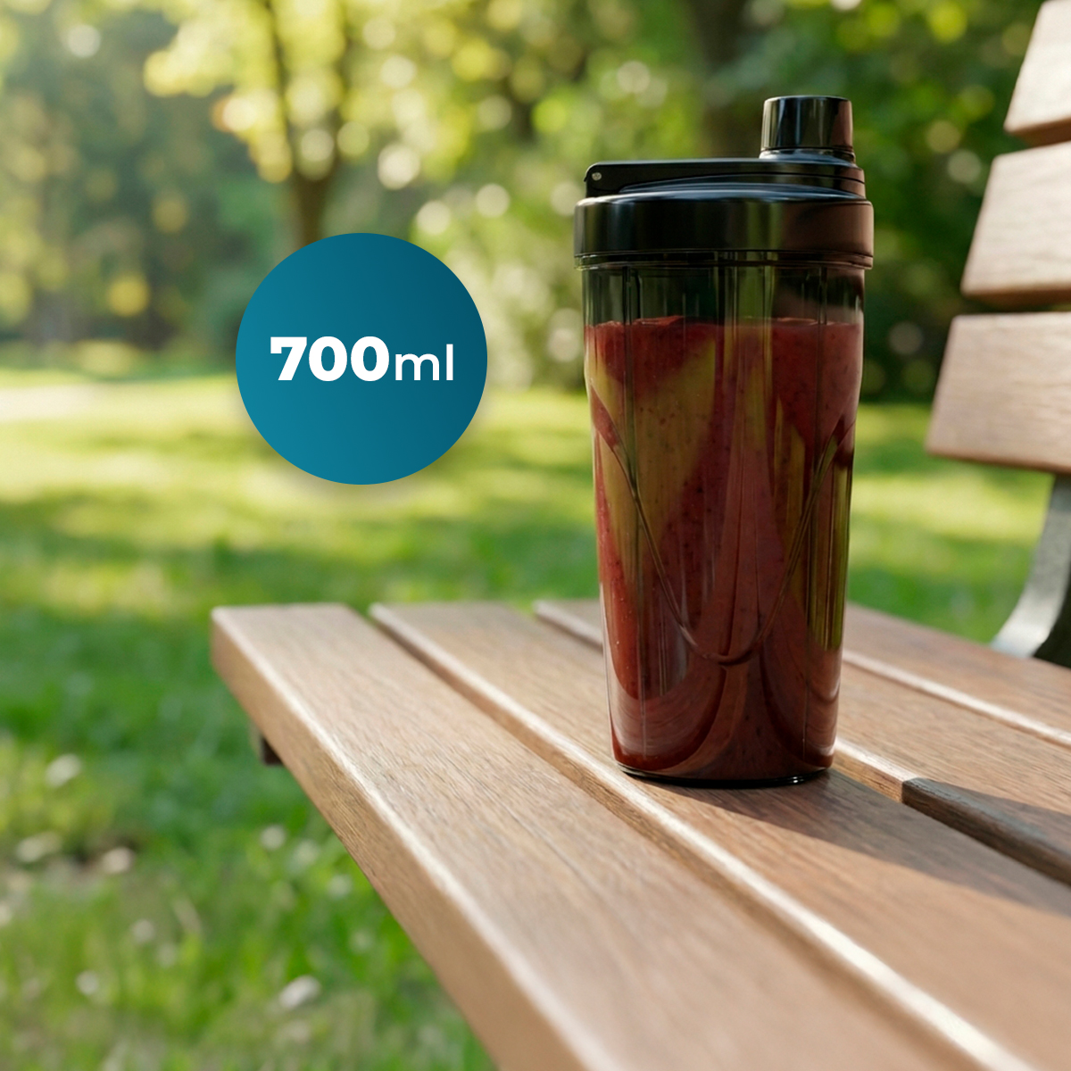Una botella mezcladora de 700 ml con un batido rojo sobre un banco de madera.