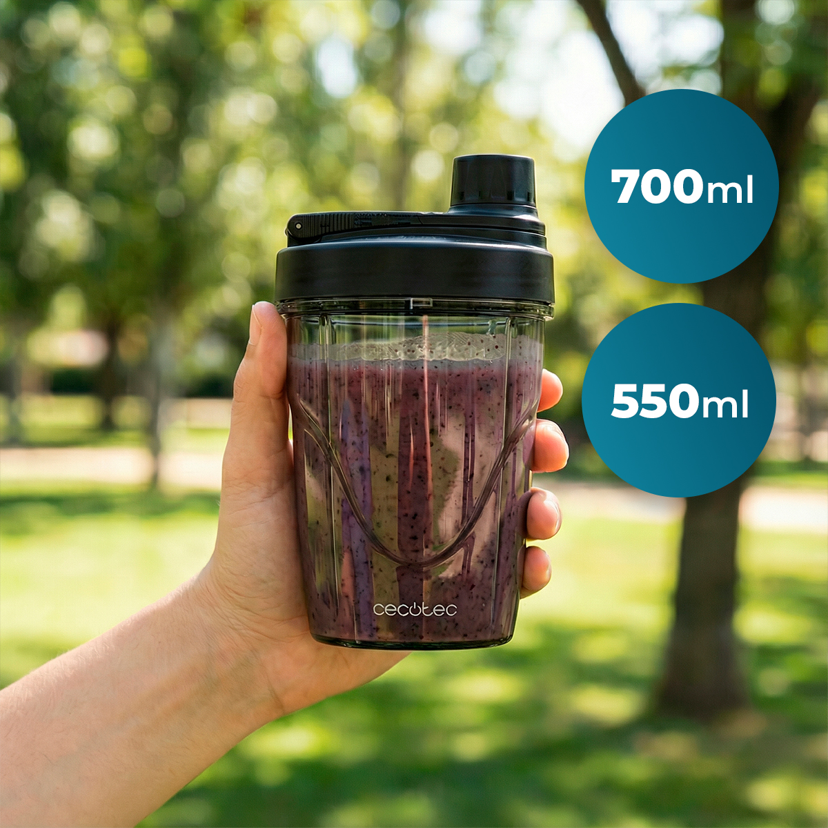 Mano sostiene vaso portátil con batido morado al aire libre, texto de 700ml y 550ml.