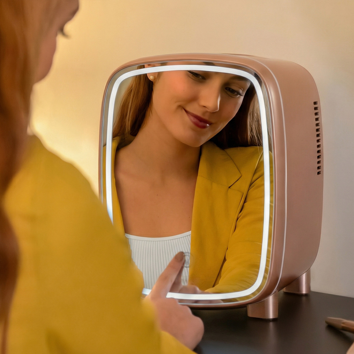 Una donna con una giacca gialla si guarda in uno specchio illuminato.