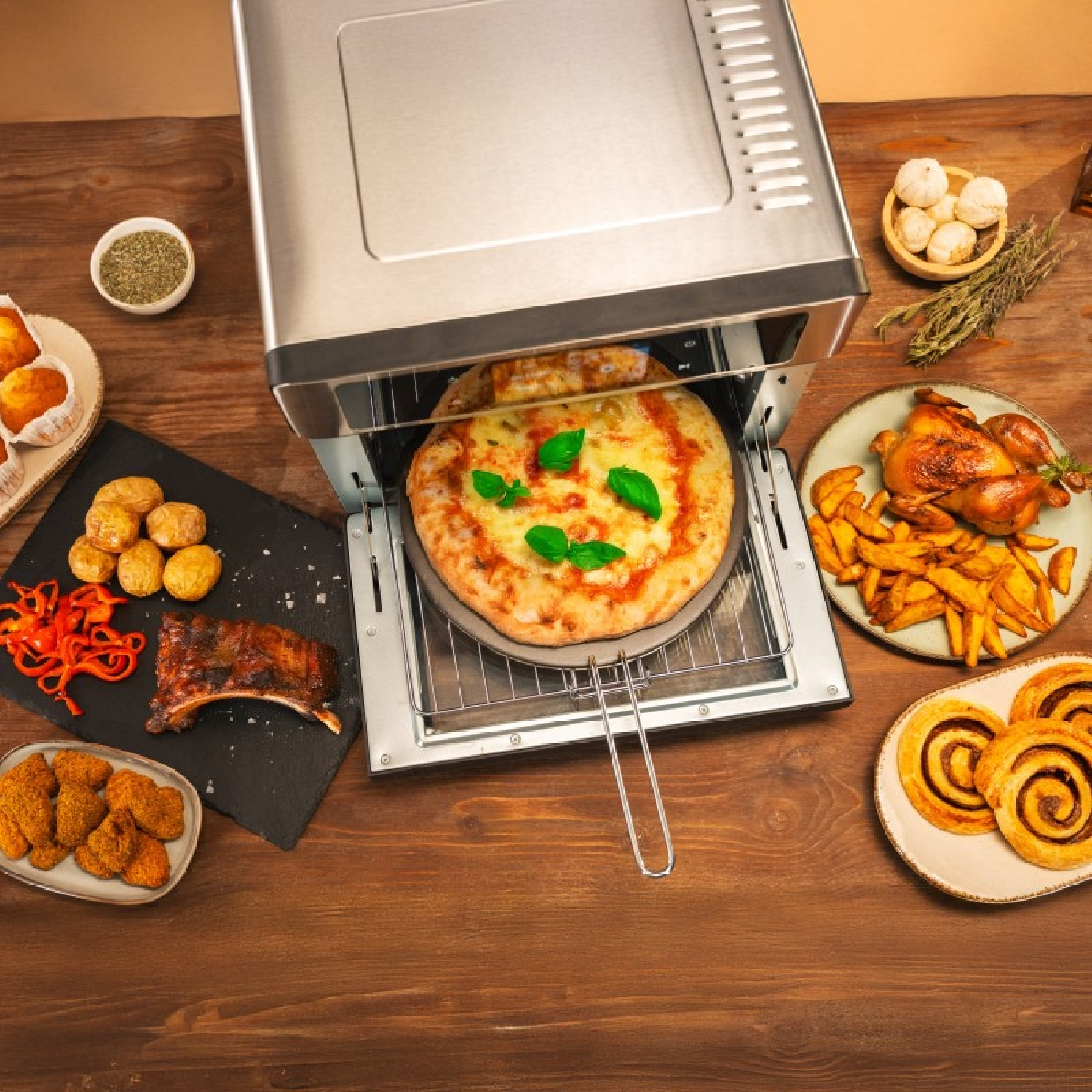 Una pizza se hornea en un horno, rodeada de pollo, papas, costillas y pasteles en una mesa de madera.