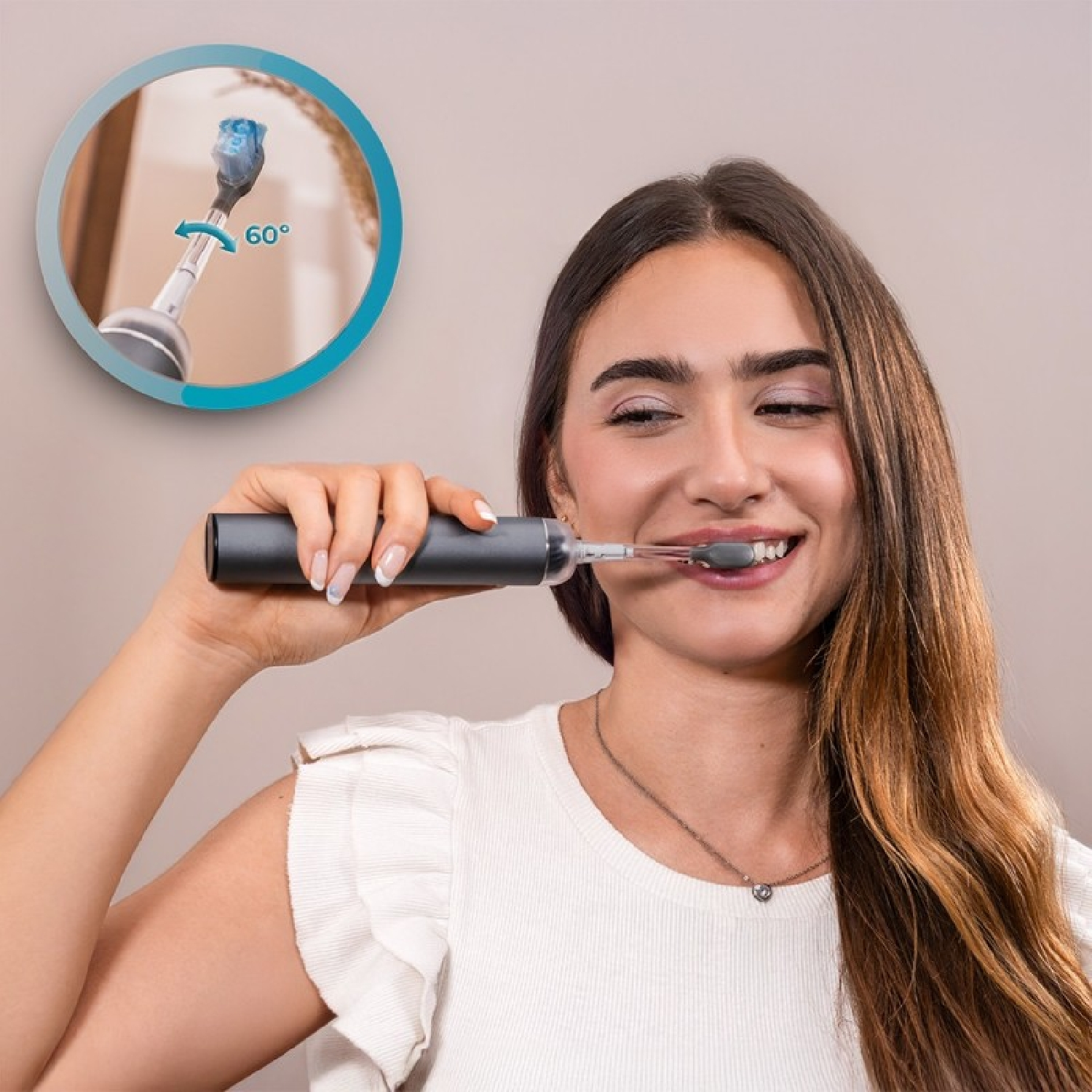 Una mujer sonríe mientras se cepilla los dientes con un cepillo eléctrico oscuro. Un inset muestra un giro de 60 grados.
