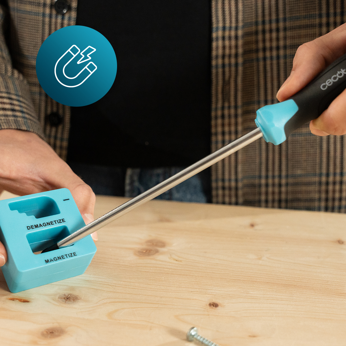 Un cacciavite viene magnetizzato in un blocco blu su un tavolo di legno.