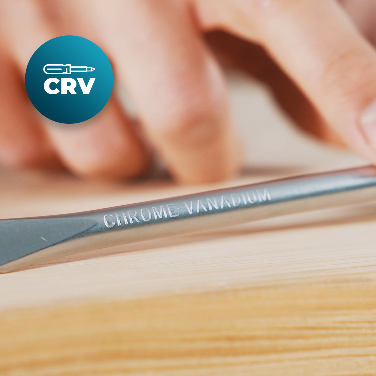 Primo piano di un utensile in cromo vanadio su legno, dita sullo sfondo e logo CRV.