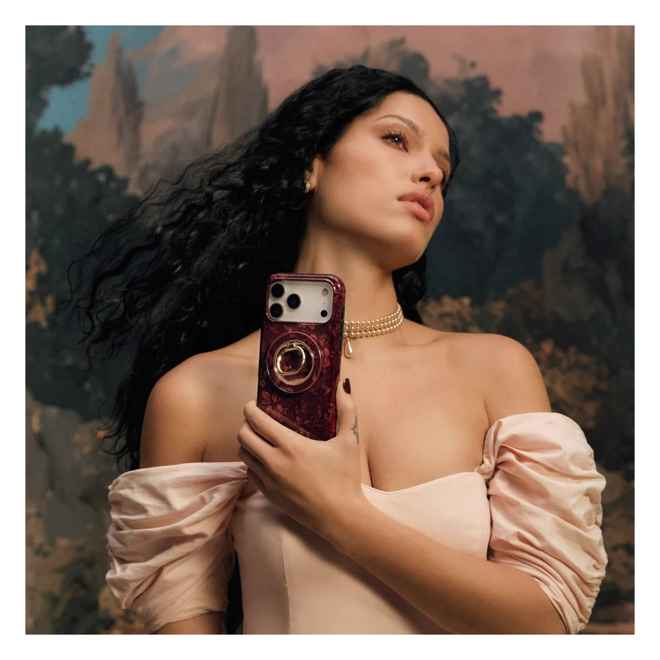 A woman in a pink dress holding a red smartphone in front of a painted background.