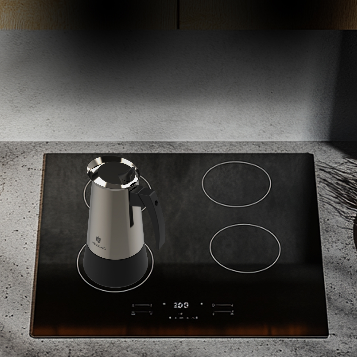 Una cafetera plateada y negra sobre una placa de inducción negra en una cocina.