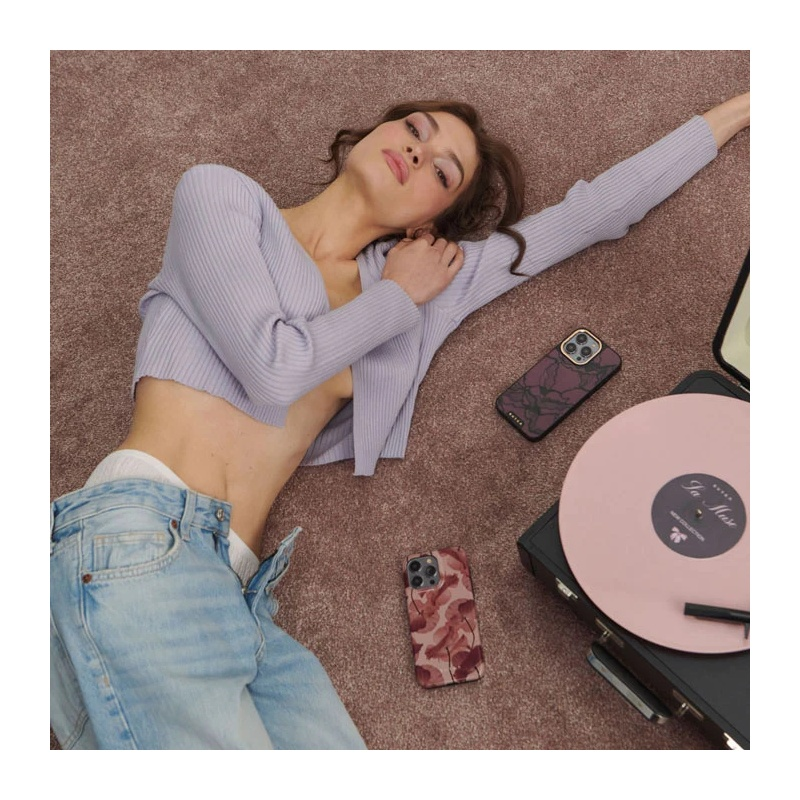 A woman in a lilac knit top and jeans lies on a brown carpet next to a record player.