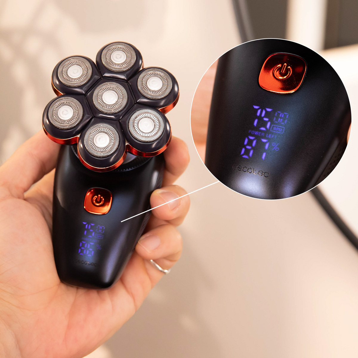 Una mano tiene un rasoio elettrico nero e oro con sei testine e display digitale.