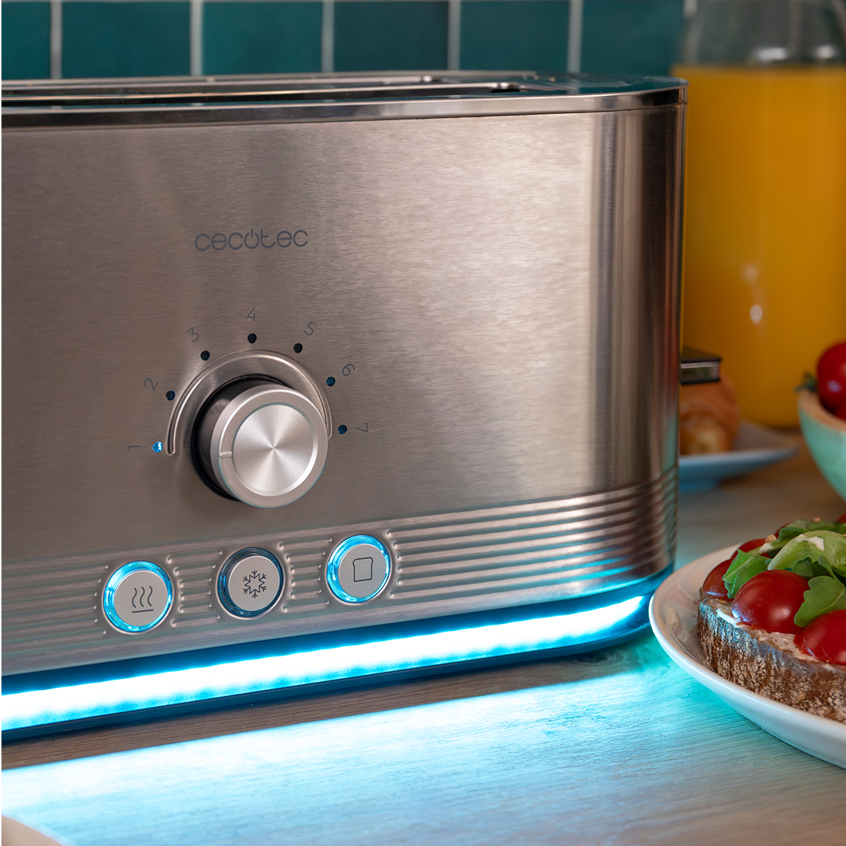 Tostadora de acero inoxidable con luz azul, mando y botones en una encimera de madera con comida.