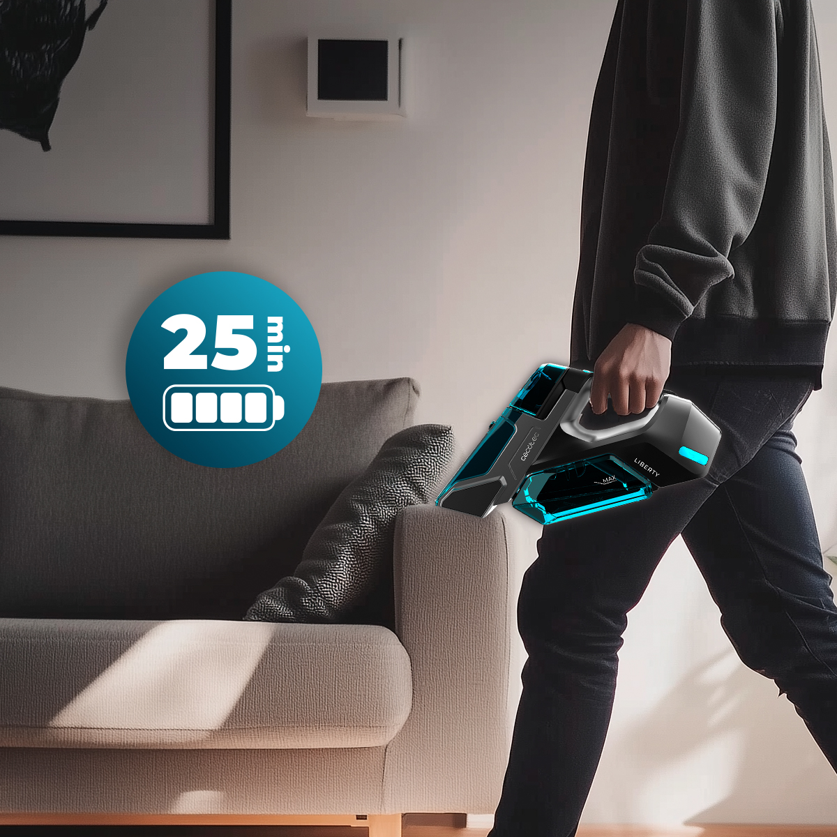 Persona cammina vicino a un divano grigio con un aspirapolvere portatile blu. Un'icona mostra 25 min di batteria.