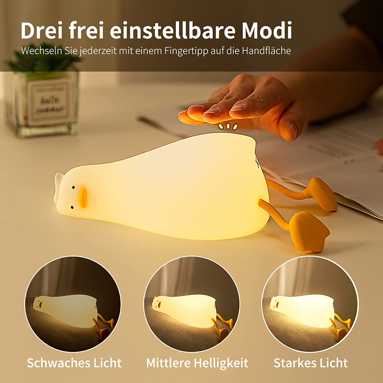 Eine Hand tippt auf eine entzückende, leuchtende Entenlampe mit drei Helligkeitsstufen auf einem Tisch.