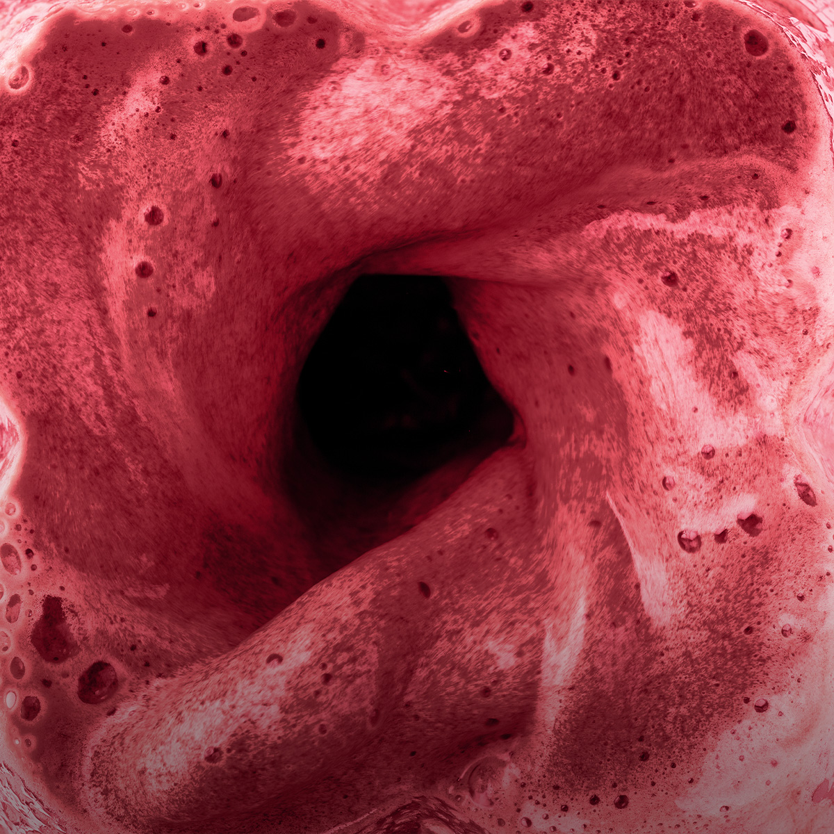 Un batido rojo gira dentro de una licuadora, creando un vórtice oscuro en el centro.