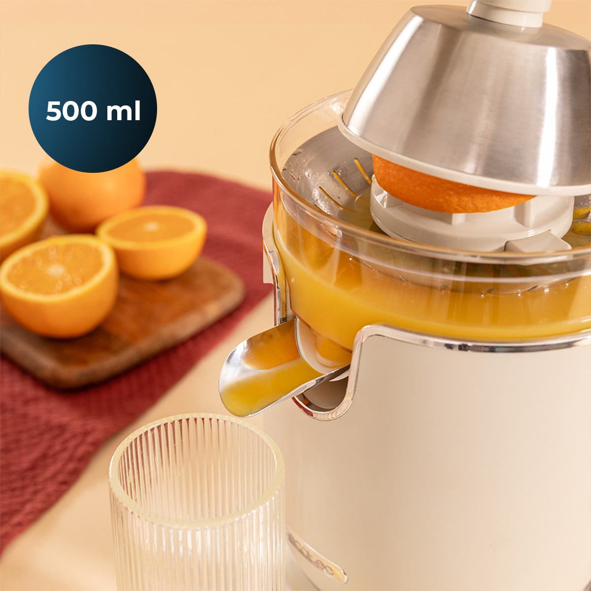 Uno spremiagrumi elettrico spreme un'arancia, riempiendo un bicchiere di succo. Arance e un'etichetta da 500 ml.