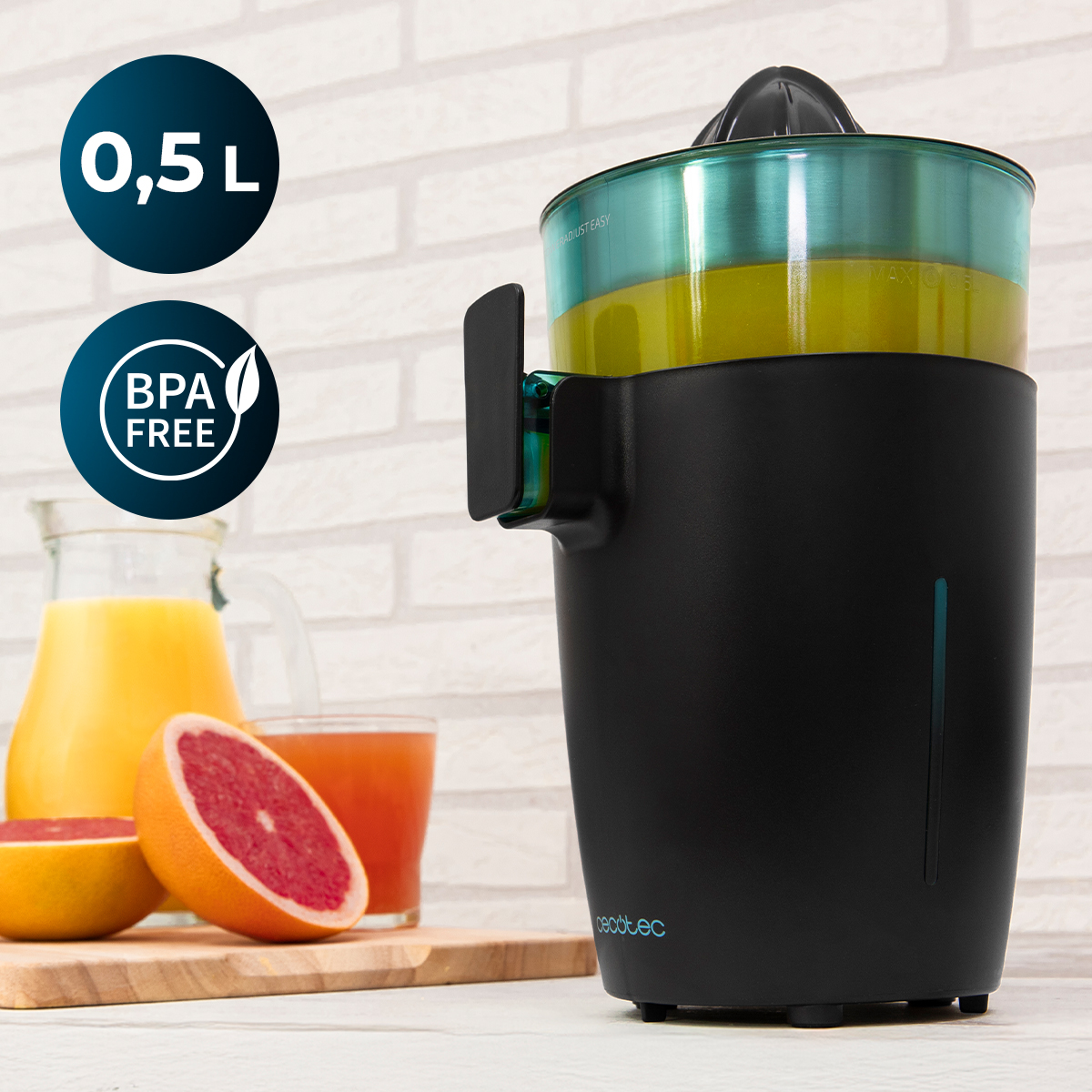 Un exprimidor negro está en un mostrador con pomelos y jugo contra una pared de ladrillos.