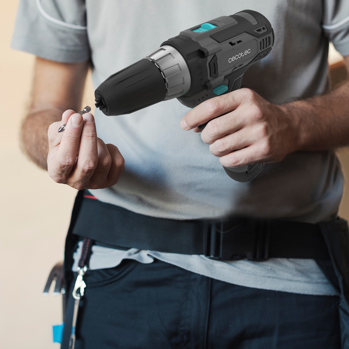 Un lavoratore tiene in mano un trapano a batteria grigio e nero e una piccola punta.