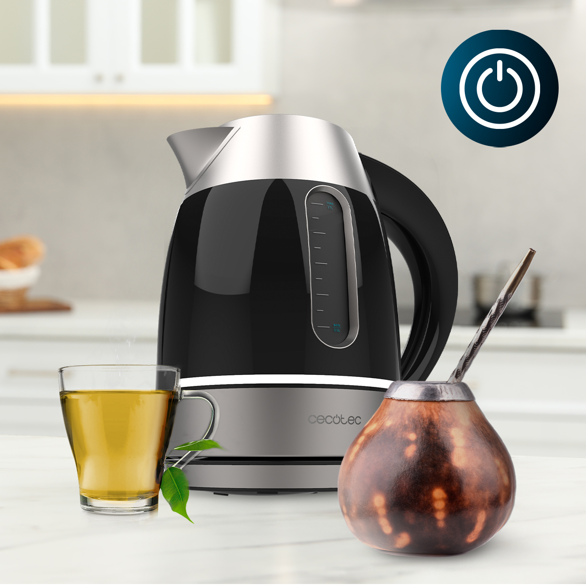 Un hervidor eléctrico negro y plateado en una encimera con un vaso de té y un mate.