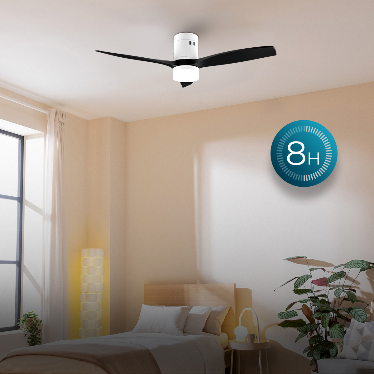Un ventilador de techo blanco y negro con luz en un dormitorio luminoso con cama y planta.