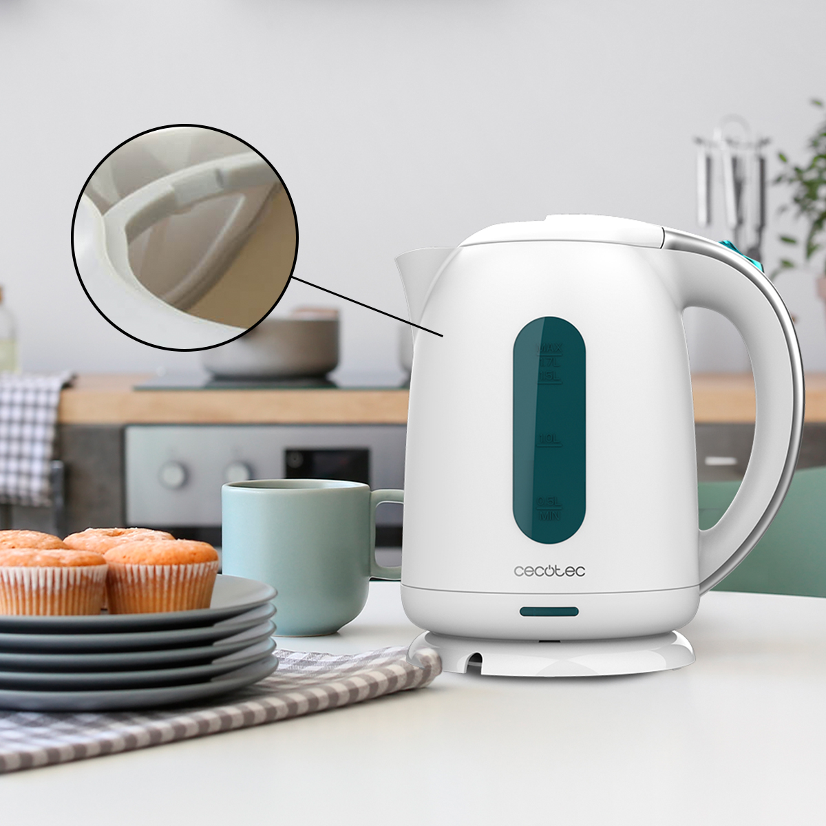 Hervidor eléctrico blanco con medidor de agua en una mesa de cocina junto a magdalenas.