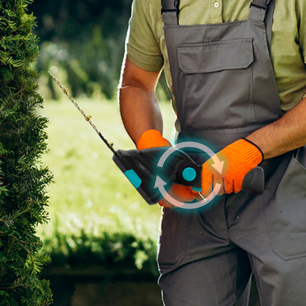 Jardinero con mono gris y guantes naranjas sostiene un cortasetos junto a un arbusto verde.