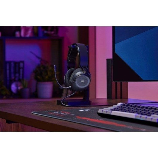 Cuffie da gioco nere su un supporto su una scrivania con tastiera e monitor.