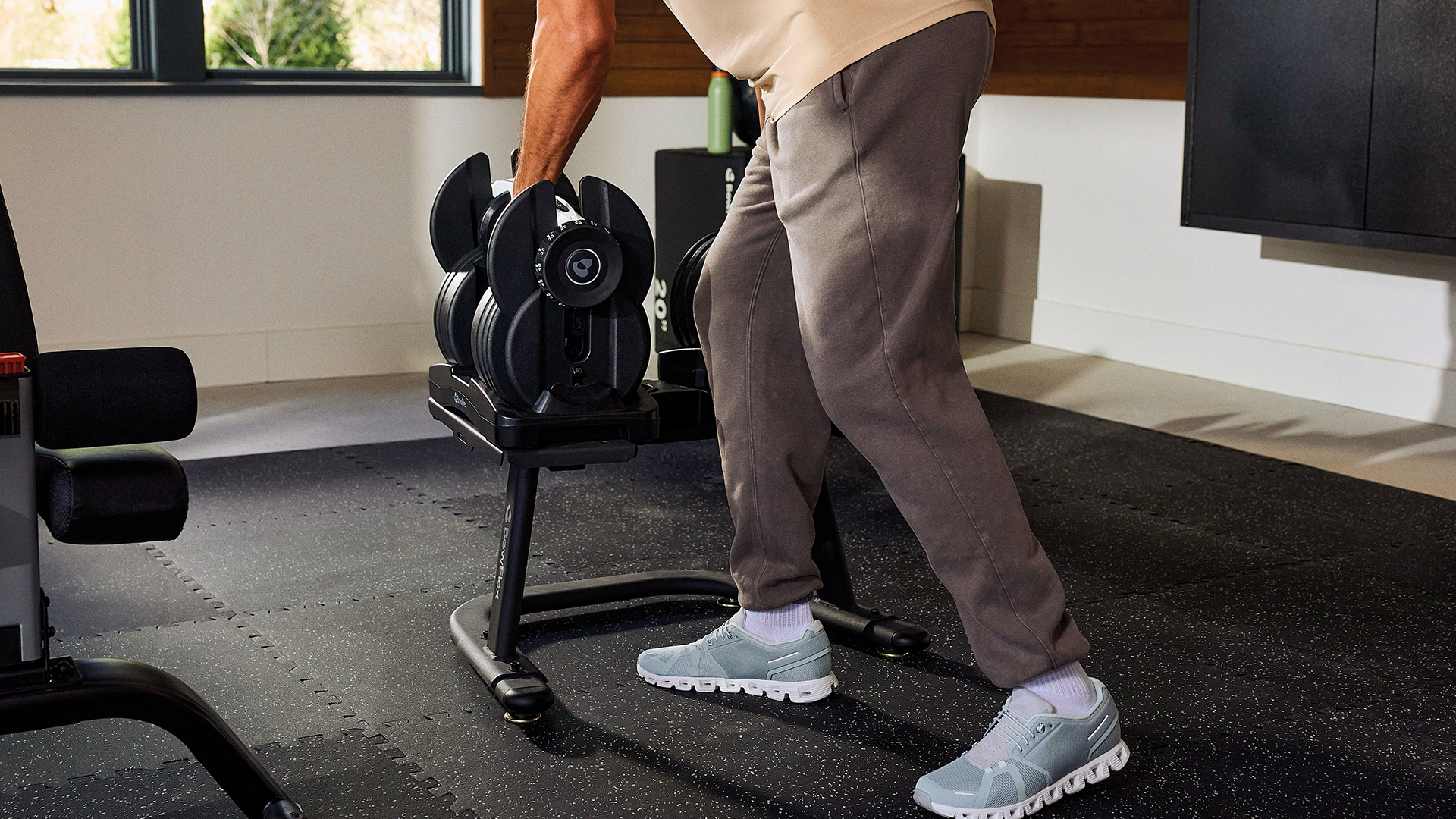Eine Person hebt eine verstellbare Hantel im Fitnessstudio auf.
