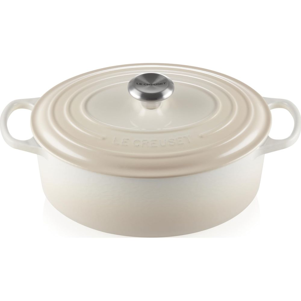 Une cocotte en fonte blanche Le Creuset avec couvercle assorti et bouton argenté sur fond blanc.