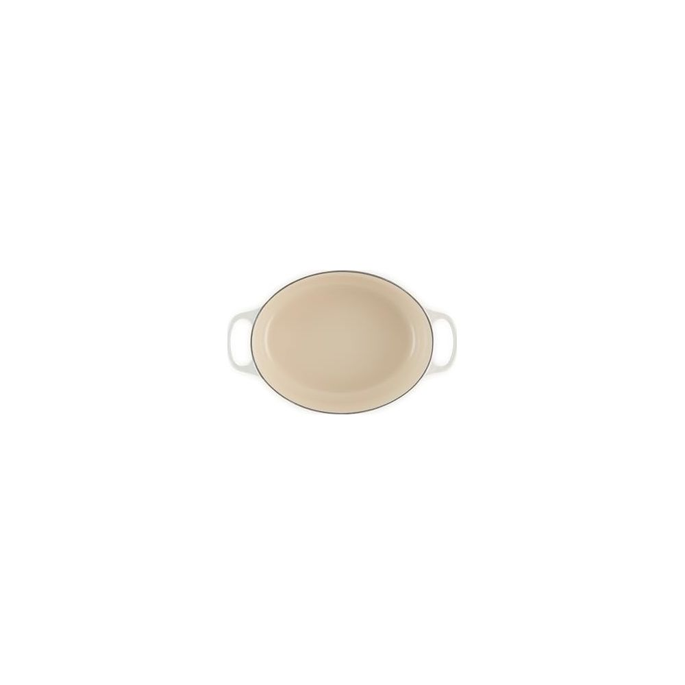 Un plat à four ovale couleur crème avec deux petites poignées sur fond blanc.