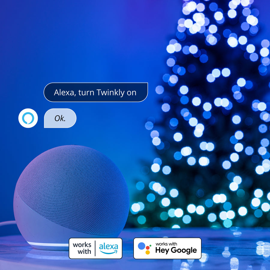 Ein blauer intelligenter Lautsprecher vor einem Weihnachtsbaum mit blauen Lichtern und Alexa-Sprechblasen.