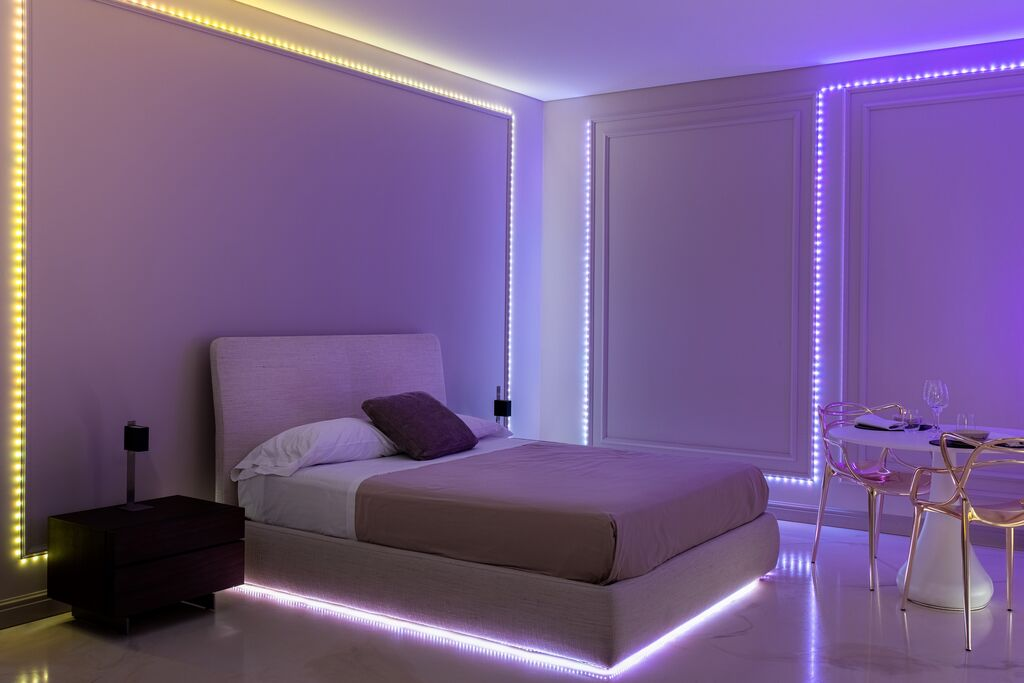 Slaapkamer met licht bed, LED-lichtstrips en een moderne tafel met stoelen.