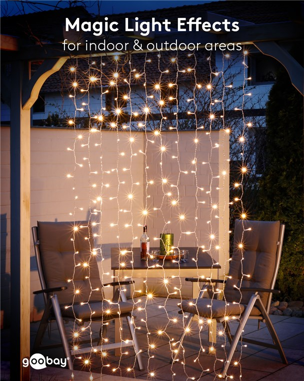 Le luci a stringa pendono davanti a un patio con tavolo e sedie la sera.