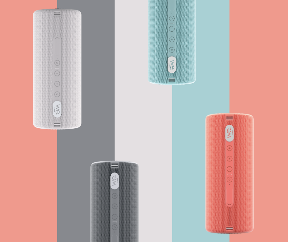 Vier farbige zylindrische Bluetooth-Lautsprecher vor einem geteilten Hintergrund in Grau, Blau und Koralle.