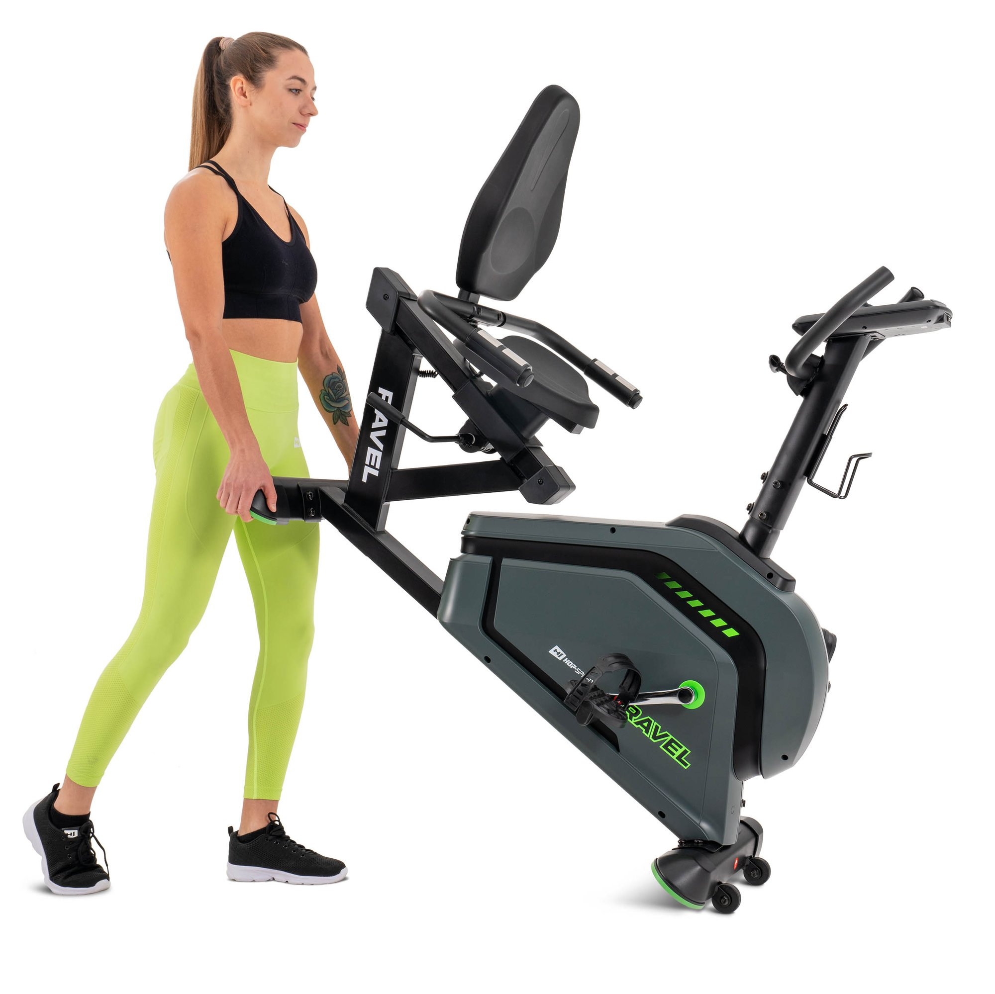 Eine Frau in Sportkleidung hält ein schwarzes Standfahrrad auf einer weißen Hintergrundfläche.