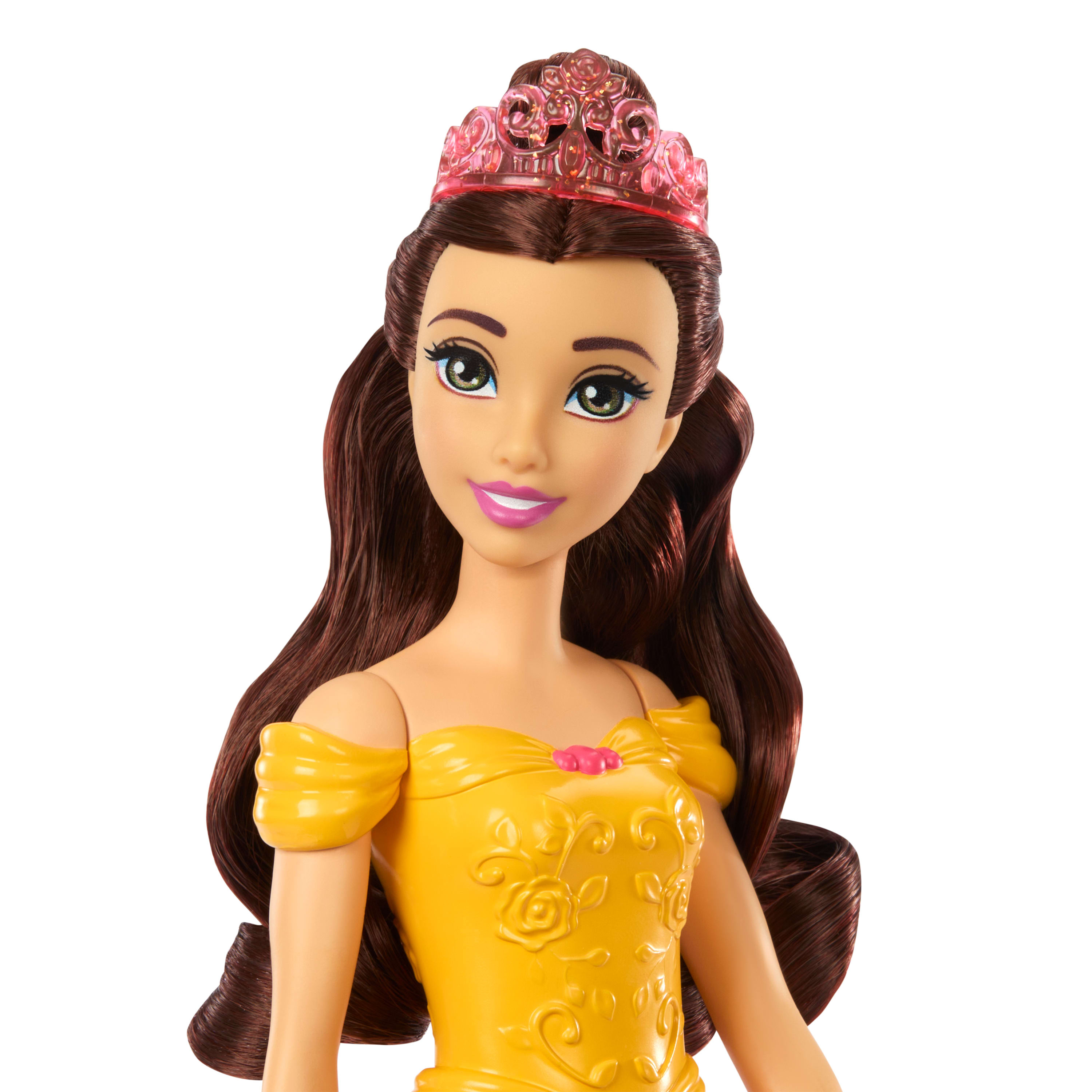 Primer plano de una muñeca con cabello castaño largo, tiara rosa y vestido amarillo sobre fondo blanco.