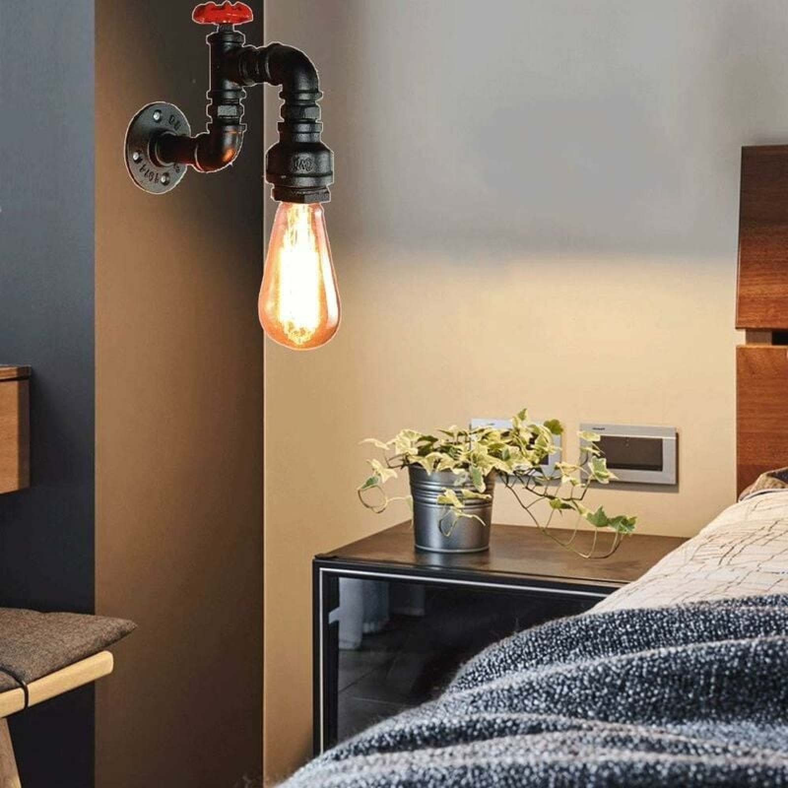 Eine leuchtende Industrie-Rohrwandlampe hängt über einem Nachttisch mit Topfpflanze neben einem Bett.