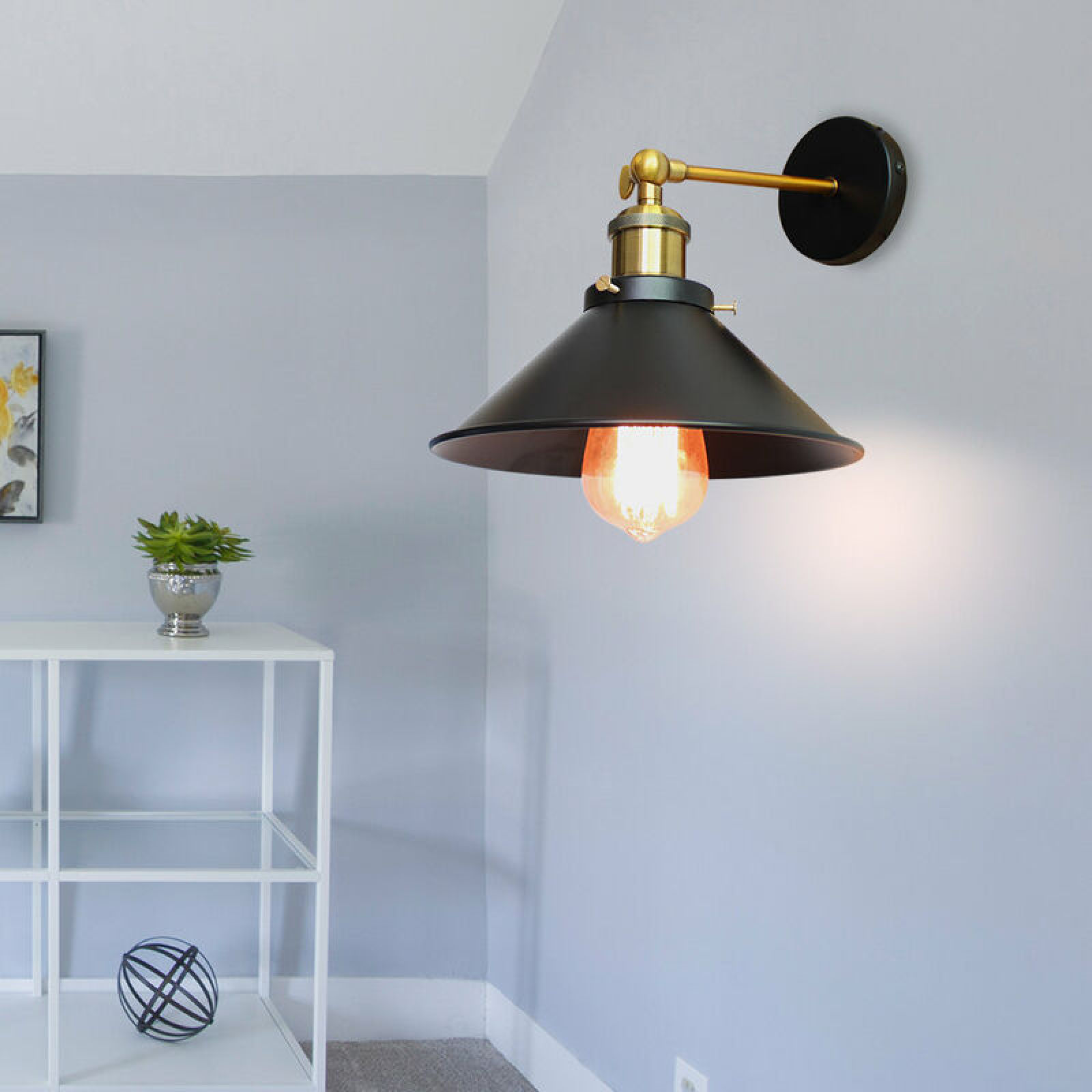 Eine schwarze Wandleuchte mit goldener Halterung und freiliegender Glühbirne an einer grauen Wand.
