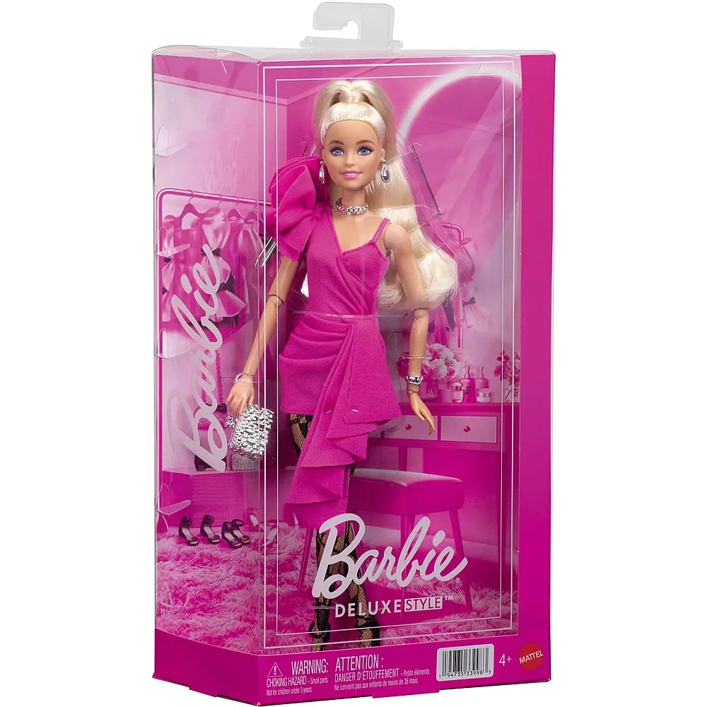Una muñeca Barbie con un vestido rosa vibrante con volantes, cabello rubio y joyas de plata en su caja.