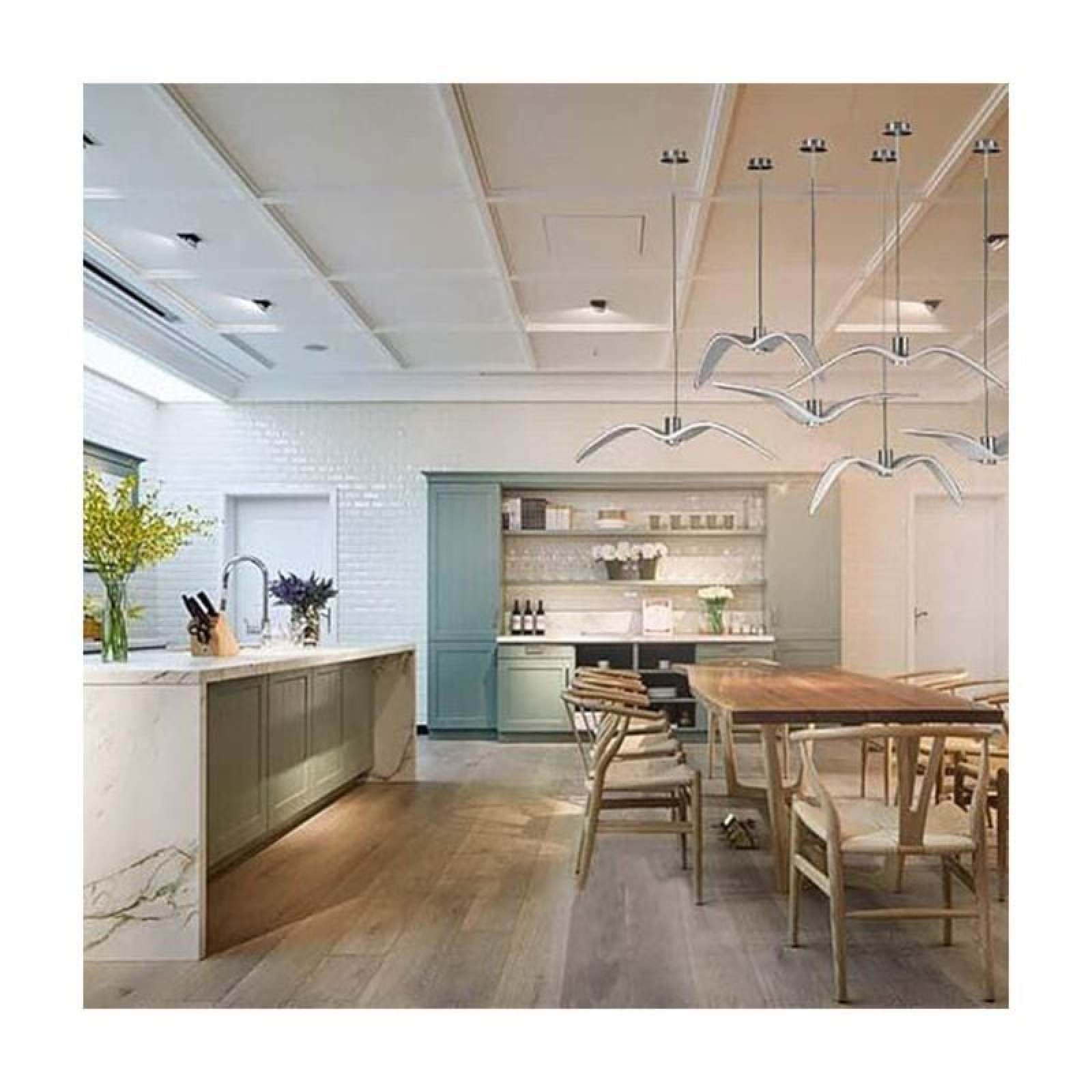 Moderne Küche mit Holzböden, Insel, Esstisch mit Stühlen und dekorativen Möwen-Hängelampen an der Decke.