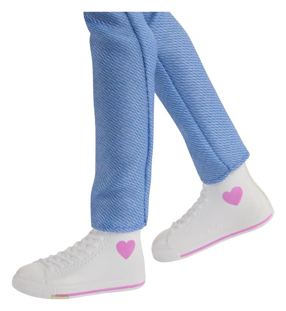Piernas de muñeca con jeans azules y zapatillas blancas con corazones rosas sobre fondo blanco.