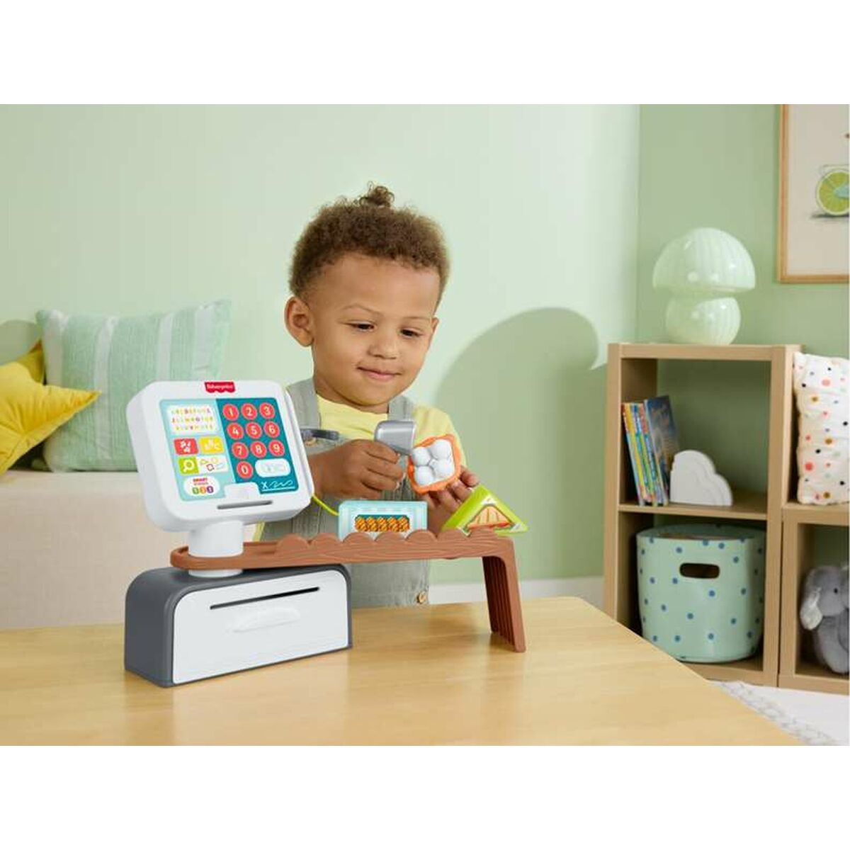 Un niño pequeño juega con una colorida caja registradora de juguete en una mesa de madera.