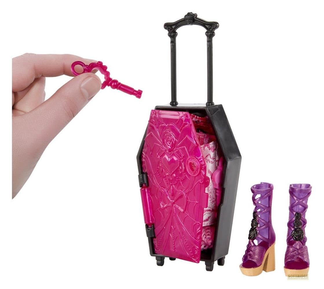 Mano sostiene llave rosa junto a una maleta con forma de ataúd y tacones morados.