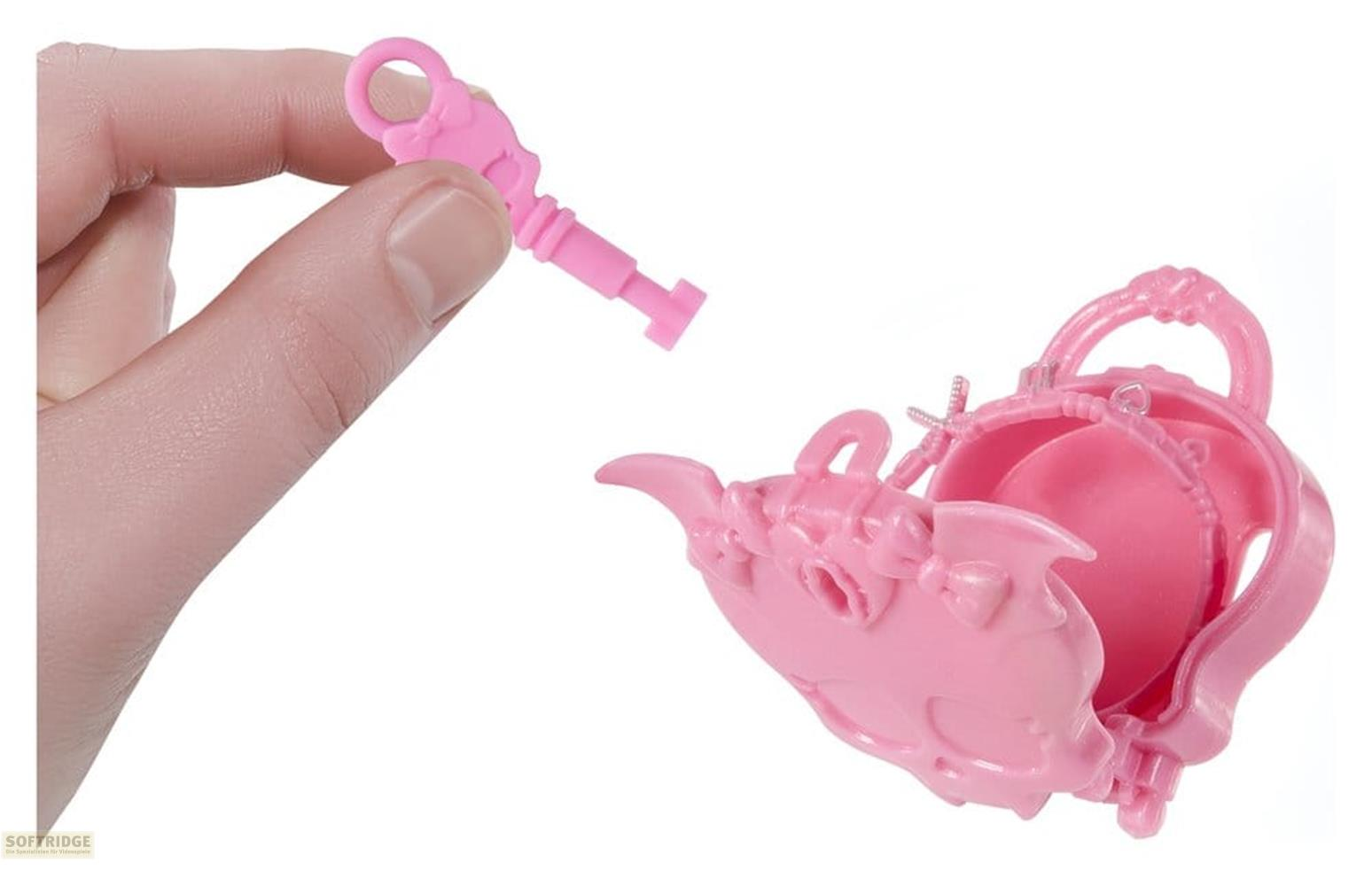 Una mano sostiene una llave de juguete rosa sobre un bolso rosa abierto con forma de calavera.