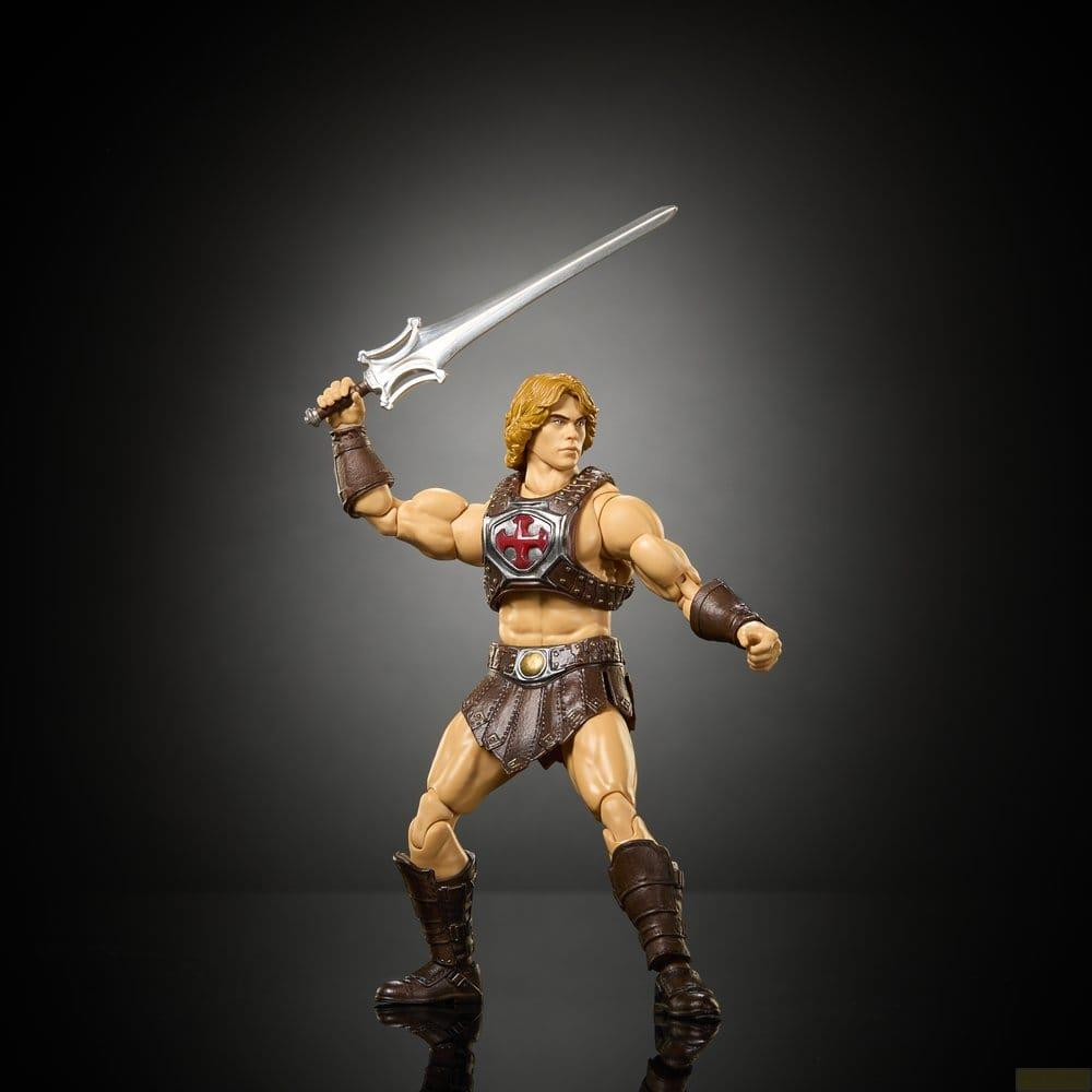 Figura de acción de He-Man con arnés y botas marrones, sosteniendo una espada plateada ante un fondo oscuro.
