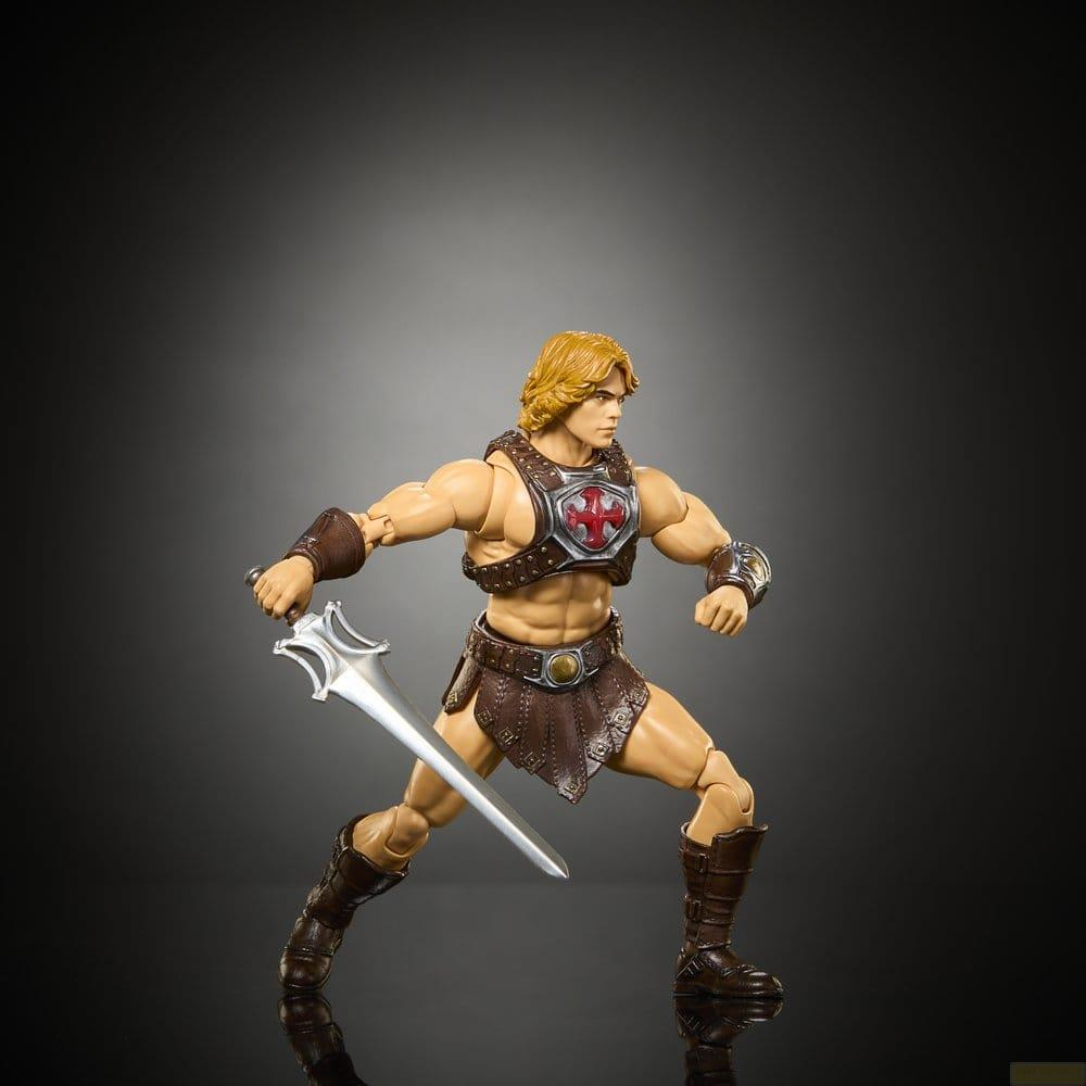 Figura de acción musculosa con cabello rubio sosteniendo una espada plateada, con armadura de cuero marrón sobre fondo oscuro.