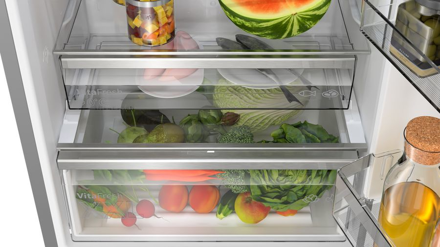 Ein offener Kühlschrank gefüllt mit frischem Obst, Gemüse, Fleisch und einem halben Wassermelone.